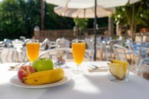 a table with a plate of fruit and two glasses of juice at Galerna Hostal in Sanxenxo