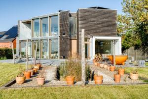 a home with potted plants in front of it at Huis van Hout - architectenwoning met grote panorama tuin - design hot tub optioneel in Herk-de-Stad