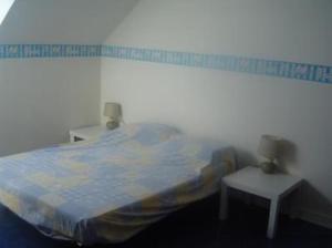 een slaapkamer met een bed en 2 kleine tafels bij Maison avec jardin et plage de sable fin accessible à pied à 300m in Saint-Coulomb