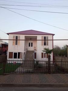 una casa bianca con una recinzione davanti di Likas haus a Kobuleti