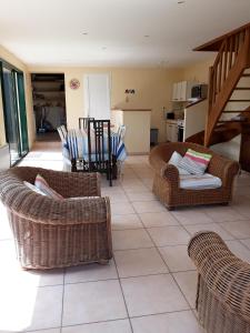 a living room with wicker chairs and a table at Maison avec jardin et plage de sable fin accessible à pied à 300m in Saint-Coulomb