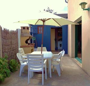 einen weißen Tisch und Stühle mit Sonnenschirm in der Unterkunft Maison avec jardin et plage de sable fin accessible à pied à 300m in Saint-Coulomb