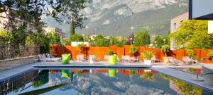 a swimming pool with tables and chairs and a mountain at Hotel Virgilio in Riva del Garda
