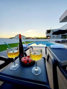 twee glazen wijn op een tafel naast een zwembad bij Apartman Villa Marina in Vodice