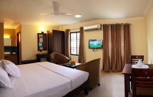 a hotel room with a bed and a television at Century Grand Hotel in Mananthavady