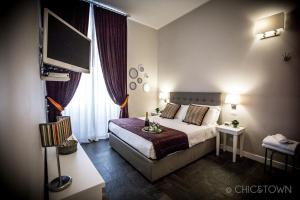 ローマにあるシック & タウン ラグジュアリー ルームズのベッド1台、薄型テレビが備わるホテルルームです。