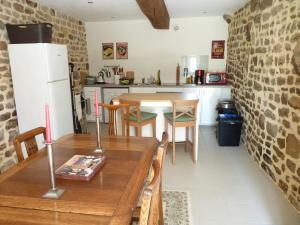 a kitchen with a wooden table with chairs and a refrigerator at La Longere in Lonlay-lʼAbbaye