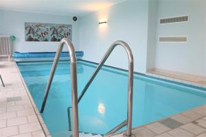 a swimming pool with blue water in a building at Haus Barbara - Schwimmbad und Sauna im Haus- Whg 5 in Grömitz