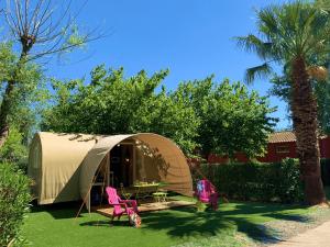 een tent met een tafel en stoelen in een tuin bij Camping Club l'Air Marin in Vias