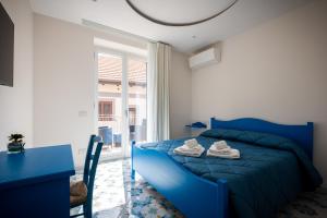 a bedroom with a blue bed and a table and a window at Palazzo San Giovanni - near Path of the Gods in Pianillo