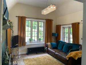 a living room with a couch and two windows at The Lodge in Cressbrook