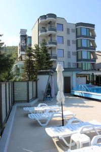 a row of lounge chairs and an umbrella on a balcony at Luander Hotel in Tirana