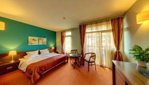 a bedroom with a bed and a table and a window at Hotel FAMIL - adults only in Bansko +85 photos