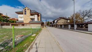 an empty street with a building and a fence at Hotel FAMIL - adults only in Bansko