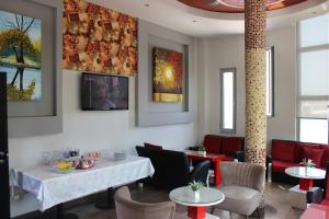 a dining room with tables and chairs and paintings on the wall at Luander Hotel in Tirana
