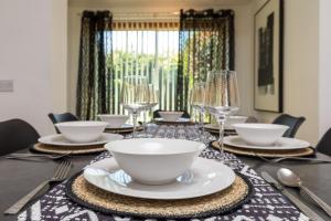 a table with plates and wine glasses on it at Findon House- Stylish & Spacious 3BR 10mins close to Airport in Crawley