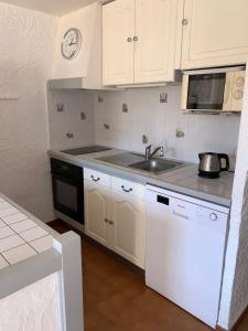 La cuisine est équipée de placards blancs, d'un évier et d'une cuisinière. dans l'établissement Résidence du Parc de la Liscia, à Calcatoggio