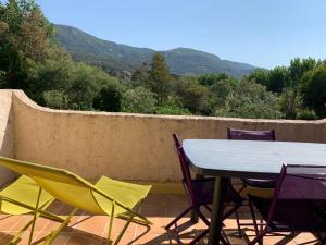 une table et des chaises sur une terrasse avec des montagnes en arrière-plan dans l'établissement Résidence du Parc de la Liscia, à Calcatoggio