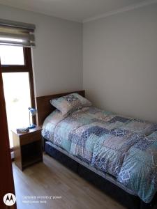 1 dormitorio con cama, mesa y ventana en Casa en Pingueral 1, en Tomé