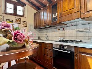 a kitchen with wooden cabinets and a vase of flowers on a counter at Monteriggioni Castello in Monteriggioni