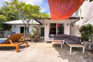 a patio with a couch and tables and a house at Pool Villa Bangrak, 2 mins to beach!!!! in Koh Samui 