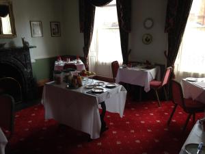 a dining room with two tables with white table cloth at Kirkgate House Hotel in Thirsk