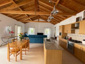 uma cozinha com tectos em madeira e uma mesa e cadeiras em A QUINTA DAS FLORES: Casa do Corvo em Santa Cruz das Flores