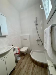 a white bathroom with a toilet and a sink at Apartments Matušan in Rab