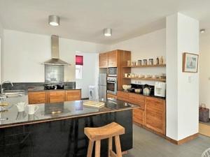 a large kitchen with a counter and a stool at So Beach Villa In Situ in Roches Noires