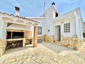 a white house with a stone wall and a fireplace at Villa Escaleta Costa dorada piscina salina y privada,barbacoa in Les tres Cales