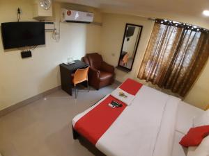 a bedroom with a bed and a chair and a television at Hotel Akash inn in Chennai
