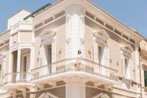 a woman standing on a balcony of a building at Le Dimore di Puglia - Palazzo Ladogana in Monopoli