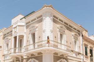 a large white building with a woman on a balcony at Le Dimore di Puglia - Palazzo Ladogana in Monopoli