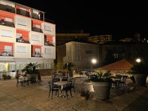 a patio with tables and chairs in front of a building at Hotel Robinia in Imperia