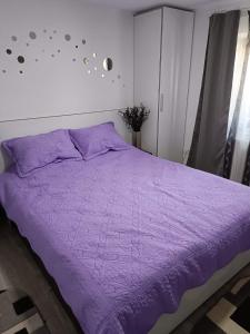 Una cama púrpura con un edredón púrpura en un dormitorio en Casa Lexi en Mangalia