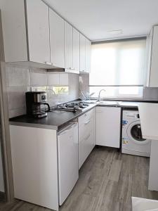 a kitchen with white cabinets and a washer and dryer at Casa Lexi in Mangalia