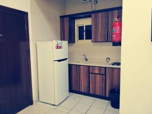 a kitchen with a white refrigerator and wooden cabinets at أسفار الأولى للشقق المخدومة in Al Multasa