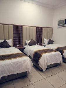 a hotel room with three beds in a room at أسفار الأولى للشقق المخدومة in Al Multasa