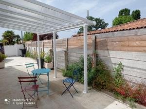 biała pergola z 2 krzesłami, stołem i krzesłami w obiekcie Studio Gujan-mestras w mieście Gujan-Mestras