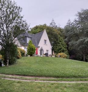 uma casa branca com uma porta vermelha num relvado em Chambres d'hôtes Saint Quinidic em Meros