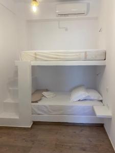 Ce lit superposé blanc se trouve dans une chambre blanche. dans l'établissement Maganiotis House, à Kimolos