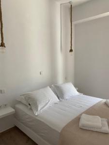 a white bedroom with a bed with two pillows at Maganiotis House in Kimolos
