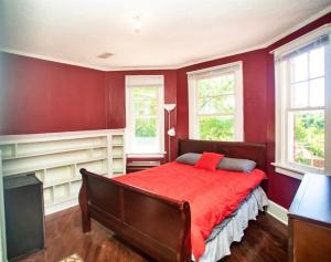 a red bedroom with a bed and two windows at Historic House on the Hill in Tuskegee