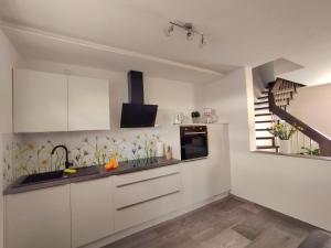 a kitchen with white cabinets and a staircase at Ferienwohnung BlumenMeer in Karlshagen