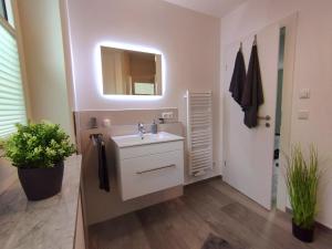 bagno con lavandino bianco e specchio di Ferienwohnung BlumenMeer a Ostseebad Karlshagen