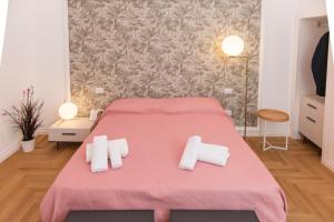 a bedroom with a pink bed with white towels on it at Le Dimore di Puglia - Palazzo Ladogana in Monopoli