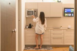 a woman standing in a kitchen looking at a microwave at Le Dimore di Puglia - Palazzo Ladogana in Monopoli