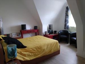 um quarto com uma cama amarela e uma cadeira em Chambres d'hôtes Saint Quinidic em Meros