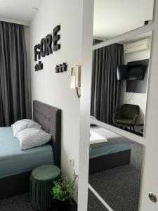 een slaapkamer met een spiegel, een bed en een stoel bij FiORE self check-in in Osijek