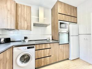a kitchen with a washer and a white refrigerator at Villa Escaleta Costa dorada piscina salina y privada,barbacoa in Les tres Cales